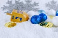 Hanukkah decorations including gelt, sparkly ornaments and a dreidel in snow. Royalty Free Stock Photo