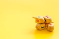 Hanukkah dreidels on yellow table. Jewish holideys concept. Close up, space for text