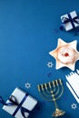 Hanukkah Jewish holiday vertical background with gold menorah, gift boxes, candles, traditional donut with jam on blue table. Flat Royalty Free Stock Photo