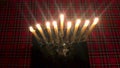 Hanukkah. Top view of a candle holder with burning candles. On the background of a red checkered tablecloth