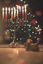 Hanukkah traditional chandelier menorah burning candles and spinning top toys dreidels on the background of Christmas tree Royalty Free Stock Photo