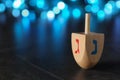 Hanukkah traditional dreidel with letters Gimel and Nun on table against blurred lights, closeup. Space for text Royalty Free Stock Photo