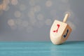 Hanukkah traditional dreidel with letters Gimel and Nun on wooden table against blurred lights. Space for text Royalty Free Stock Photo