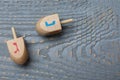 Hanukkah traditional dreidels with letters Nun and Gimel on grey wooden table, flat lay. Space for text Royalty Free Stock Photo