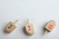 Hanukkah traditional dreidels with letters Nun, Gimel and He on white wooden table, flat lay. Space for text Royalty Free Stock Photo