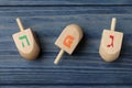 Hanukkah traditional dreidels with letters He, Pe and Gimel on blue wooden table, flat lay Royalty Free Stock Photo