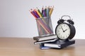 Haphazard pile of school books with alarm clock