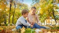 Happ family sitting on fallen yellow leaves at autumn park and eating apples