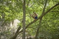 Happily smiling relaxed teenager enjoying his summer holidays sitting on a thick branch in a mediterranean rocky forest