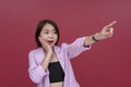 A happily surprised asian woman gushes while pointing to the right. Covering her mouth, recognizing someone well known,