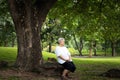 Happiness asian senior woman very calm in green nature at park,relax time,concentrate elderly people sit under the tree, feel