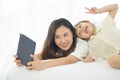 Happiness Asian young mother and little cute daughter lying on bed in the house using laptop for take photo Royalty Free Stock Photo