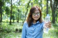 Happiness Beautiful asian chinese women holding mineral water bottle. Young Woman Drinking Water from bottle in green garden Park Royalty Free Stock Photo