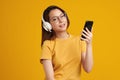 Happiness Beautiful Asian smiling young woman wearing technology wireless  headphones for listening the music via smart mobile Royalty Free Stock Photo