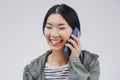 When happiness calls, answer it. Studio shot of a young woman using a mobile phone against a grey background. Royalty Free Stock Photo