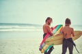 Happiness comes in waves. a young couple walking on the beach with their surfboards. Royalty Free Stock Photo