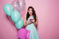 Happiness, consumerism, sale and people concept - smiling young woman with shopping bag and balloons over pink Royalty Free Stock Photo