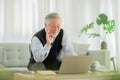 Happiness elderly asian man sitting on sofa and using computer laptop VDO Conference online meeting with family or business team Royalty Free Stock Photo