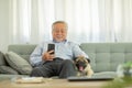 Happiness elderly asian man sitting on sofa and using mobile phone and smile with dog pug breed at cozy home,Portrait of wellness