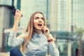 Happiness good news. woman celebrating fists up talking at phone, earphone looking up isolated near corporate business center