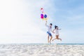 Happiness lover couple holding colorful balloons and jumping with smile on the tropical beach in sunny day Royalty Free Stock Photo