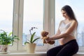 Pregnant young happy woman with toy teddy bear, at home near window Royalty Free Stock Photo