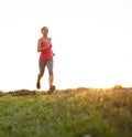 Happiness is running. A beautiful young woman jogging as the sun sets behind her.