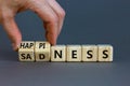 Happiness or sadness symbol. Businessman turns cubes and changes the word `sadness` to `happiness`. Beautiful grey background.