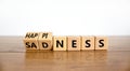 Happiness or sadness symbol. Turned cubes and changed the word `sadness` to `happiness`. Beautiful wooden table, white backgro