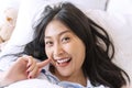 Happiness smiling woman using smartphone for selfie on the bed for social media. Cheerful girl lying on white bed taking Royalty Free Stock Photo
