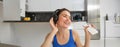 Happiness, sports and wellbeing. Young woman dancing in headphones, holding smartphone, doing workout at home, fitness Royalty Free Stock Photo