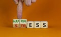 Happiness instead of stress. Businessman turns a cube and changes the word `stress` to `happiness`. Beautiful orange backgroun