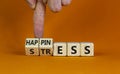 Happiness instead of stress. Businessman turns a cube and changes the word `stress` to `happiness`. Beautiful orange backgroun