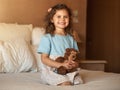 Happiness thrives at a young age. an adorable little girl at home sitting on her bed happy as can be with her teddybear.