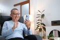 Happiness of wellness elderly asian man with white hairs sitting on sofa using mobile phone