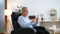 Happiness of wellness elderly asian man with white hairs sitting on sofa using mobile phone