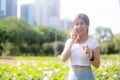 Happiness young asian woman standing and talking on smart phone in the park, girl relaxation and receiving smartphone. Royalty Free Stock Photo