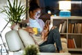 Happiness young entrepreneur woman using her smart phone while drinking a cup of coffee sitting on couch in the office Royalty Free Stock Photo