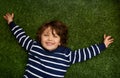 Happy, above and portrait of child on grass for relax, playful fun and happiness in garden. Family, nature and young boy Royalty Free Stock Photo