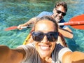 Happy active adult couple enjoying kayak canoe excursion trip tour on transparent blue clean water at the sea. Concept of