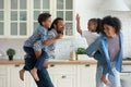 Happy active African parents piggybacking sibling children, running in kitchen Royalty Free Stock Photo