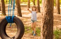 Happy active child girl playing on swing wheel in forest on sunny summer day. Preschool child having fun and swinging on a tire Royalty Free Stock Photo