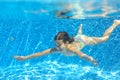 Happy active child swims underwater in pool