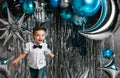 Happy active kid boy has fun with silver blue metallic balloons for birthday party on background with free copy space Royalty Free Stock Photo