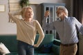 Happy active retired elder couple dancing together in living room