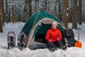 happy active tourist sits in winter forest