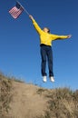 happy active woman joyfully jump up raising american flag against cloudless blue sky Royalty Free Stock Photo