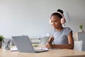 Happy adolescent afro american female student with headphones studying at home watching online lesson Royalty Free Stock Photo