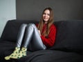 Happy adorable adult woman sitting on grey sofa