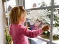 Happy adorable baby girl sitting near window and looking outside on snow on Christmas day or morning. Smiling healthy Royalty Free Stock Photo